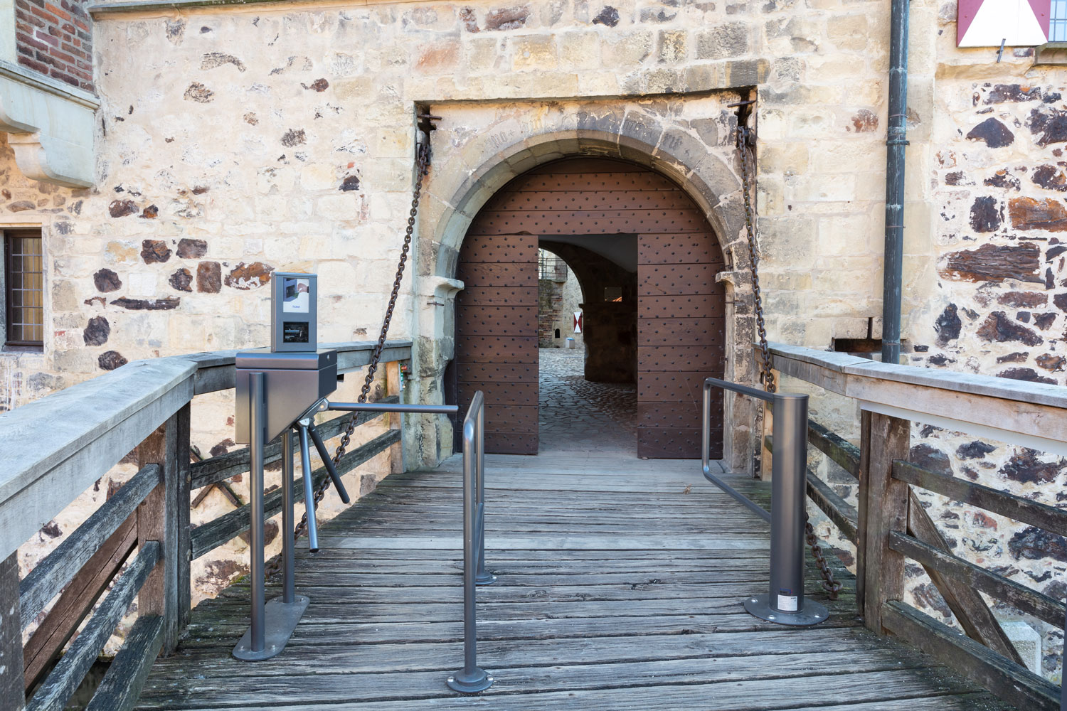 Tor für Rollstuhlfahrer und Rollstuhlfahrerinnen neben dem Drehkreuz auf der hölzernen Brücke zur Burg