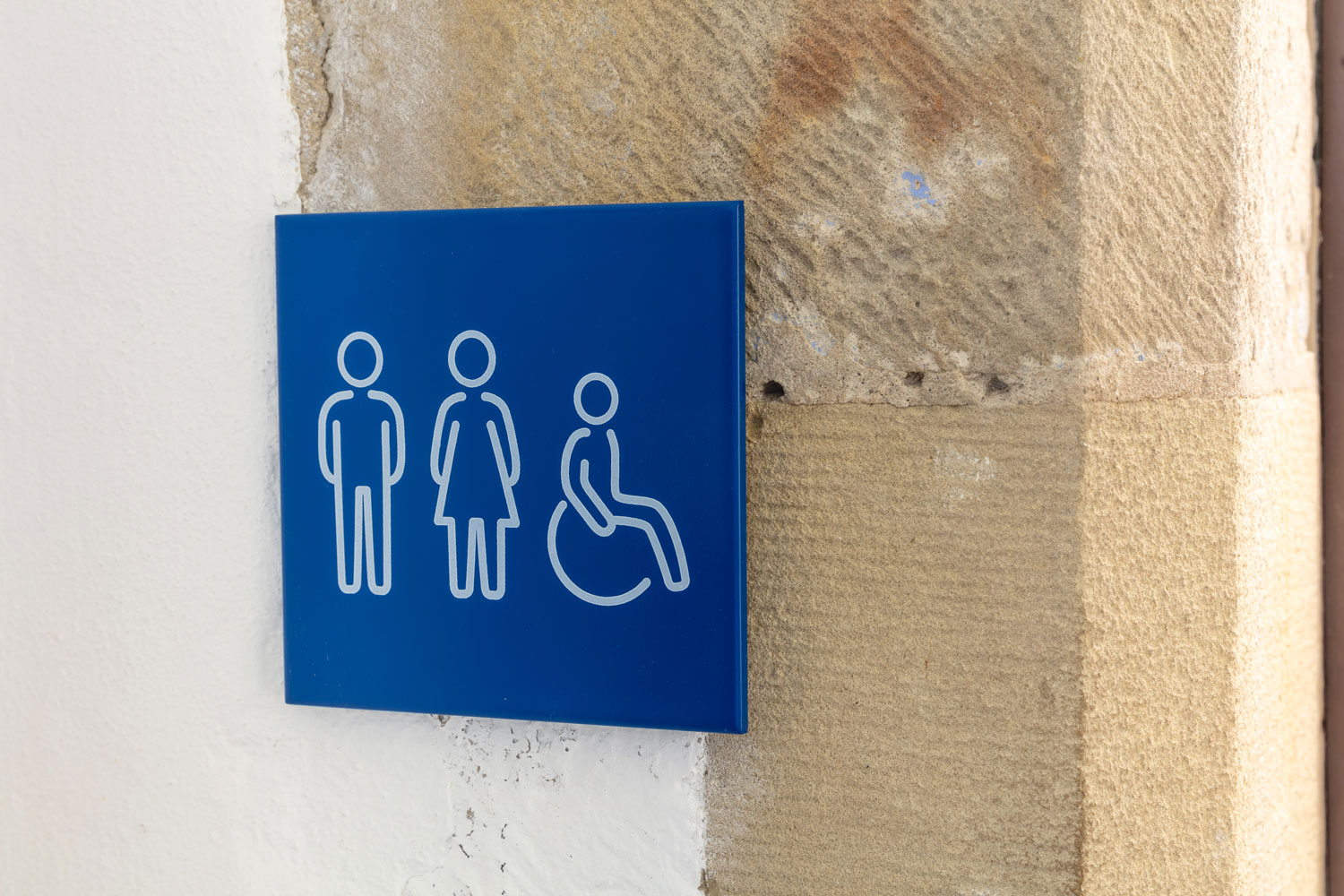 Blaues Schild, das die behindertengerechten Toiletten ausweist